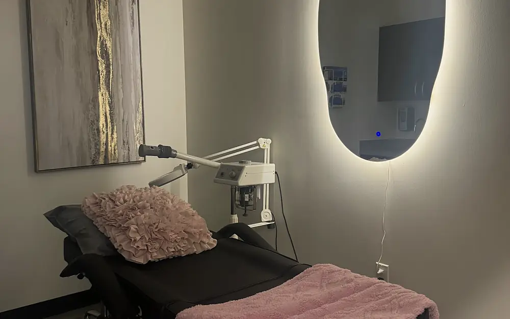 A PISO treatment room with a massage table and backlit mirror